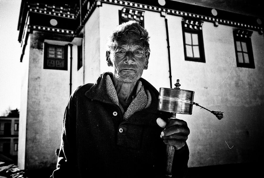 Tibetan pilgrim spinning a prayer wheel at a Bir monastery