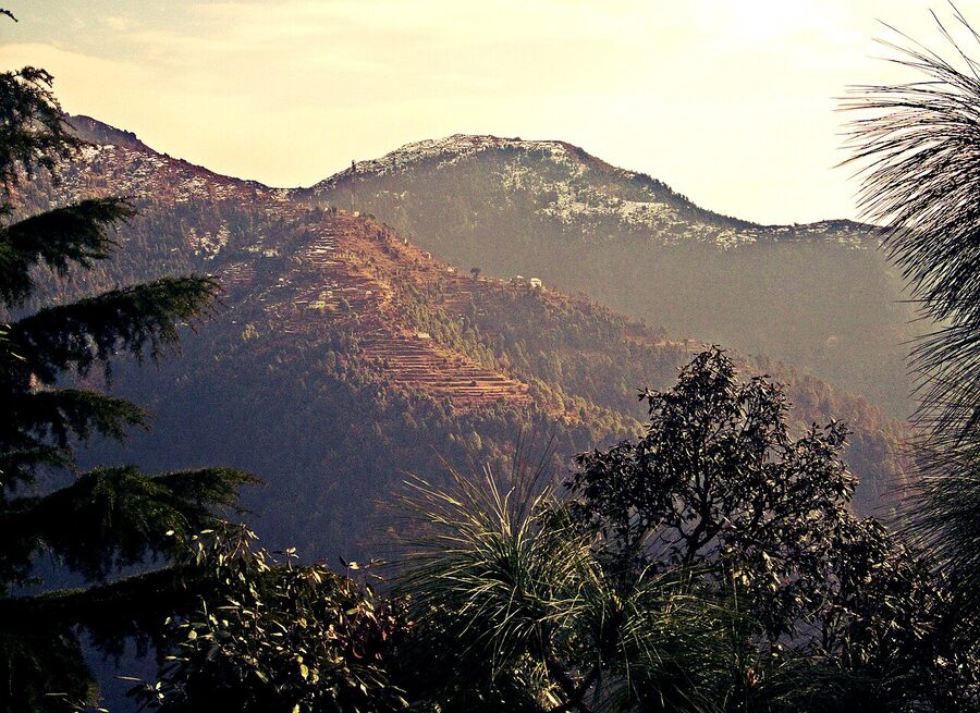 Dalhousie hill station showing colonial-era stone cottages on a ridge surrounded by deodar trees.