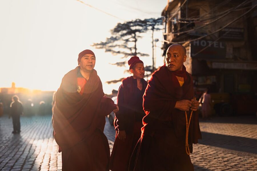 Monks in maroon robes walking through Dharamshala at sunrise.