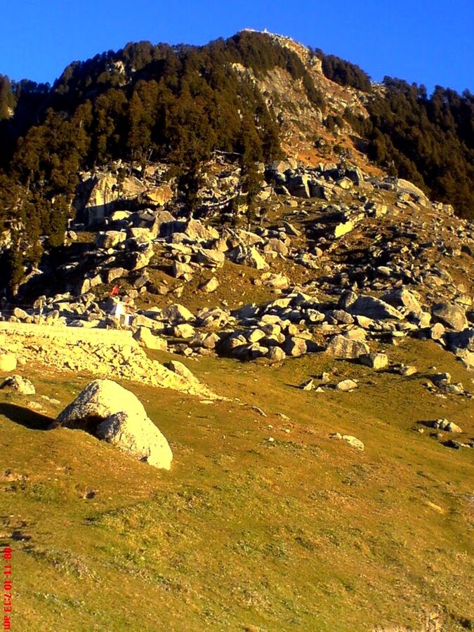 The Triund hill ridge with snow-capped Dhauladhar peaks visible behind.