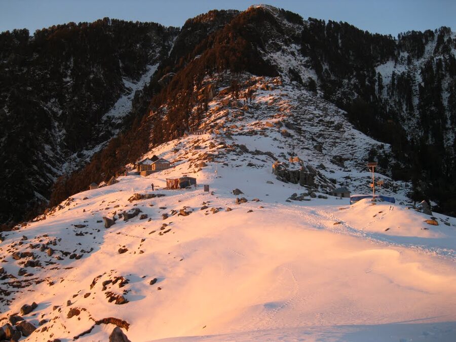 The Triund campground covered in snow with tents set against a snowy background.