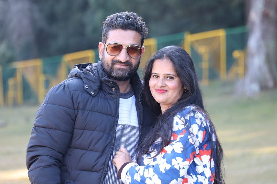 A couple sitting on a hillside in Khajjiar, Himachal Pradesh, with the meadow and forest behind them