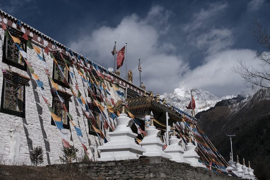 Colourful Tibetan prayer flags above a monastery against mountain backdrop