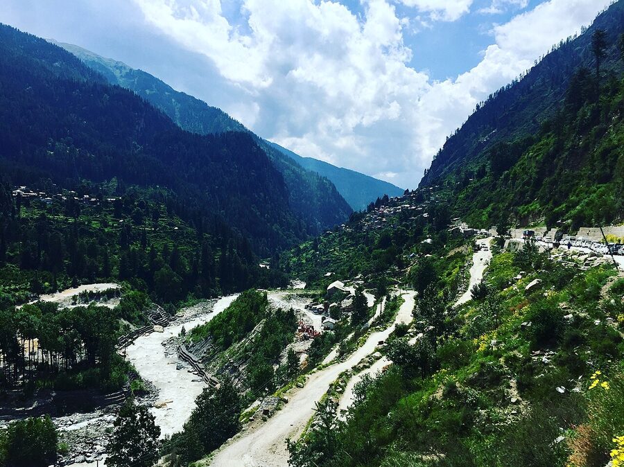 The Kheerganga meadow at sunset with snow-capped peaks rising behind.