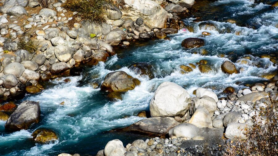 The Beas river running below Naggar in the Kullu valley with stones in the foreground.