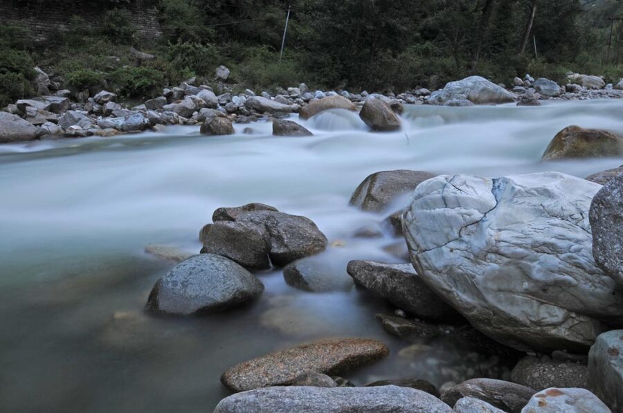 Long-exposure photograph of the Tirthan river showing milky water flow