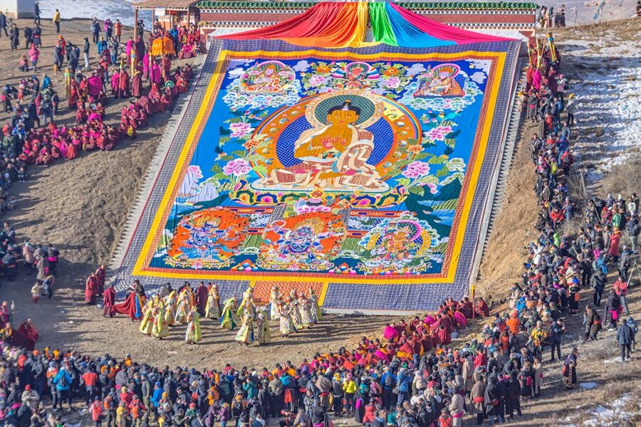 Aerial view of a Tibetan Buddhist gathering in McLeod Ganj with a large thangka and crowd.